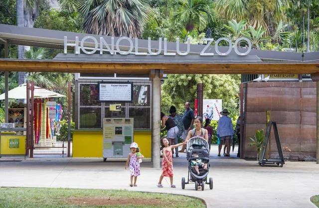 Honolulu Zoo front entrance with a mom and 2 kids walking out the Zoo.
