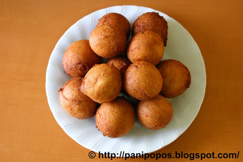 Several panikeke--cripsy, brown, fried dough balls--on a plate.