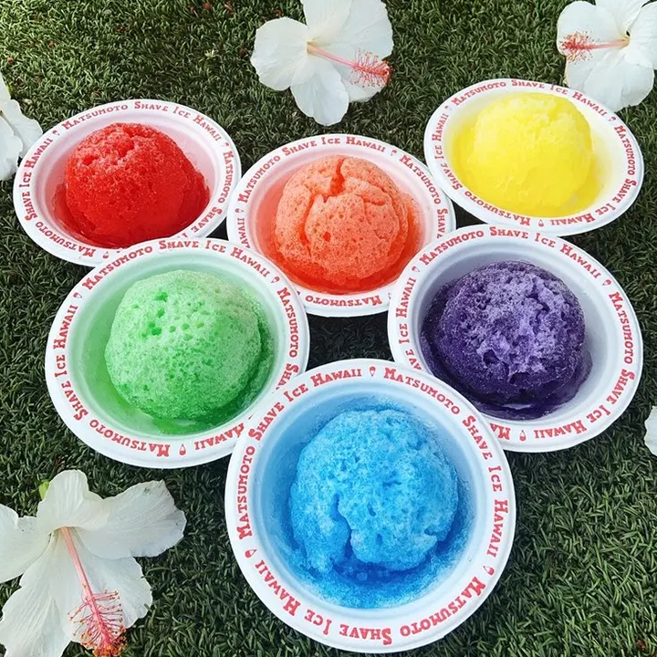 Six different flavors of shave ice in bowls.