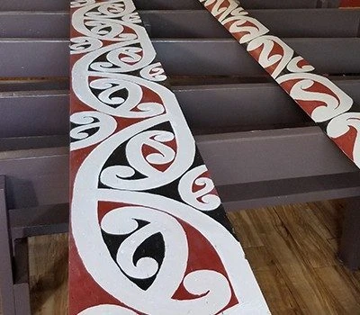 Traditional Māori Kōwaiwhai patterns painted on large panels in bright red, black, and white></p><p>The <span lang=
