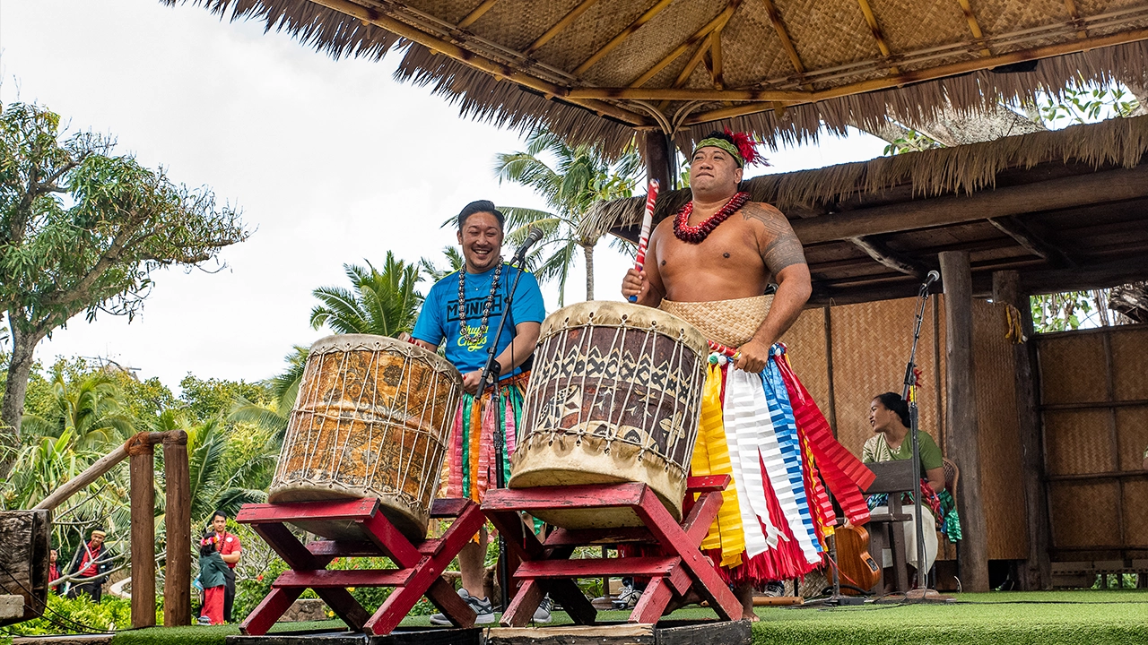 Tongan playing traditional Tongan drums with a visitor of the Center