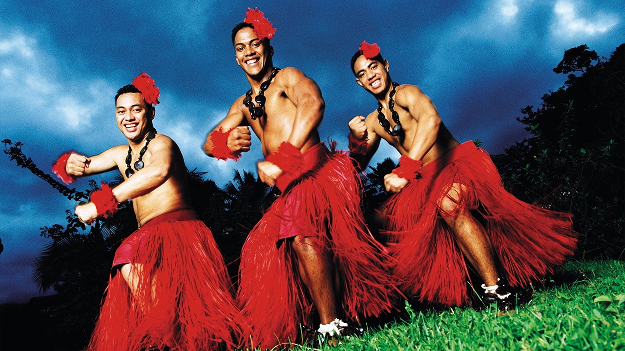 Three male Tongan dancers performing and smiling