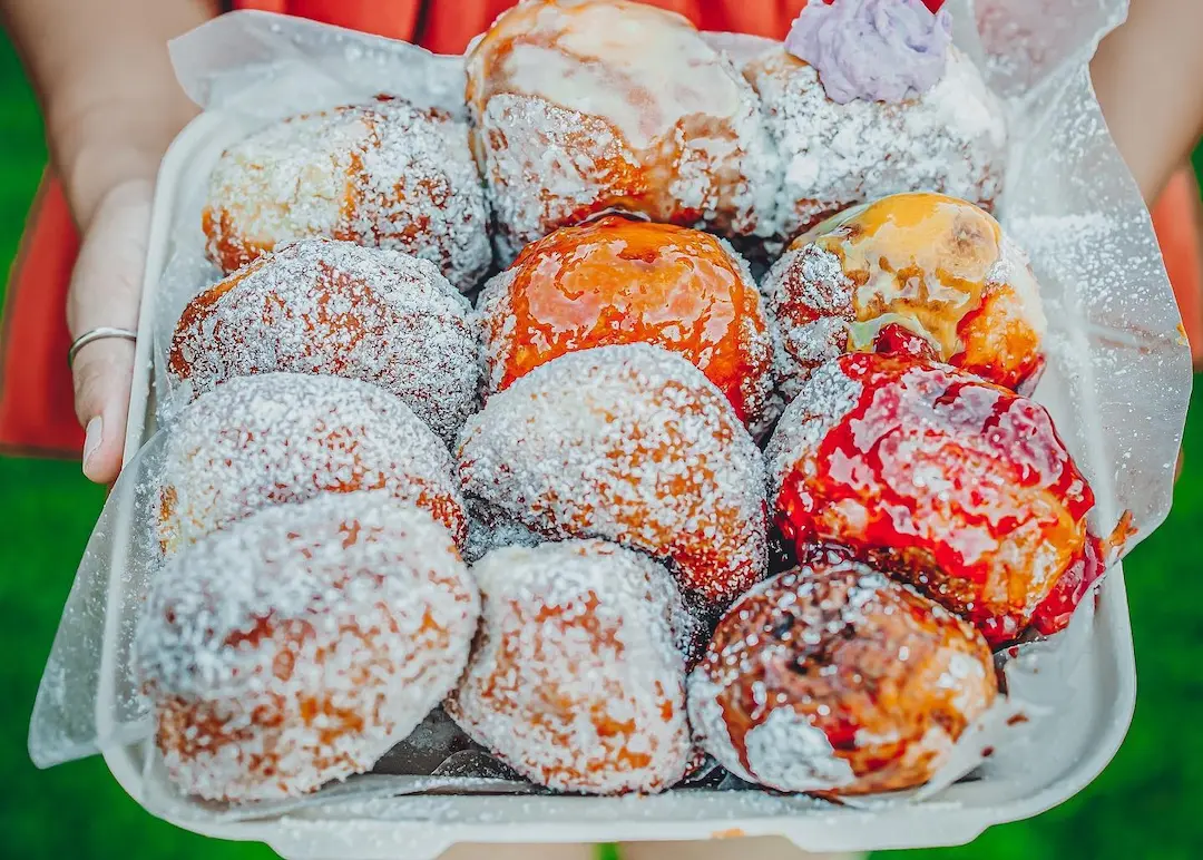 A tray of delicious, baked malasada, coated in sugar.