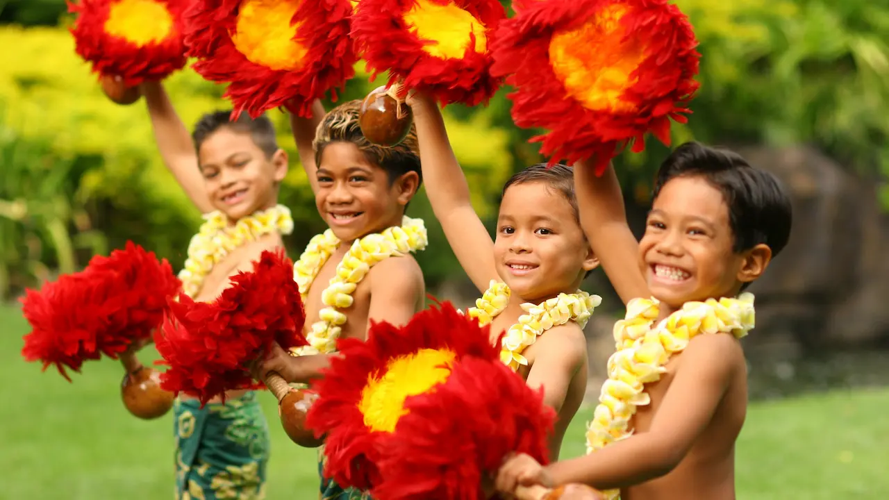 Children performing a hula with red-feathered ʻuliʻuli instruments.