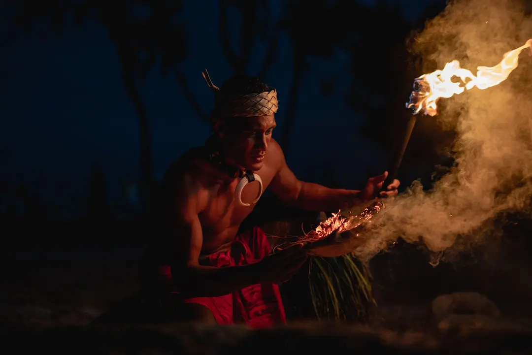 A Samoan male fireknife dancer is showing how he lights his war knife using fire and coconut husk.