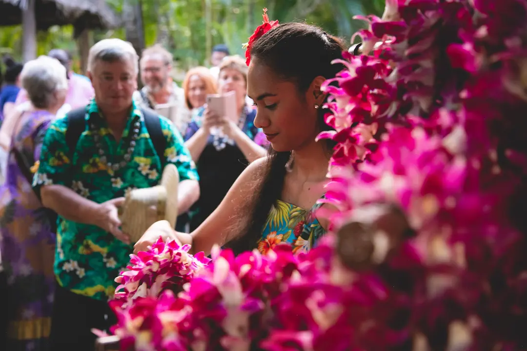  Polynesian lady greeting and welcoming the guests with fresh flower leis to the front entrance of the Aliʻi Lūʻau.