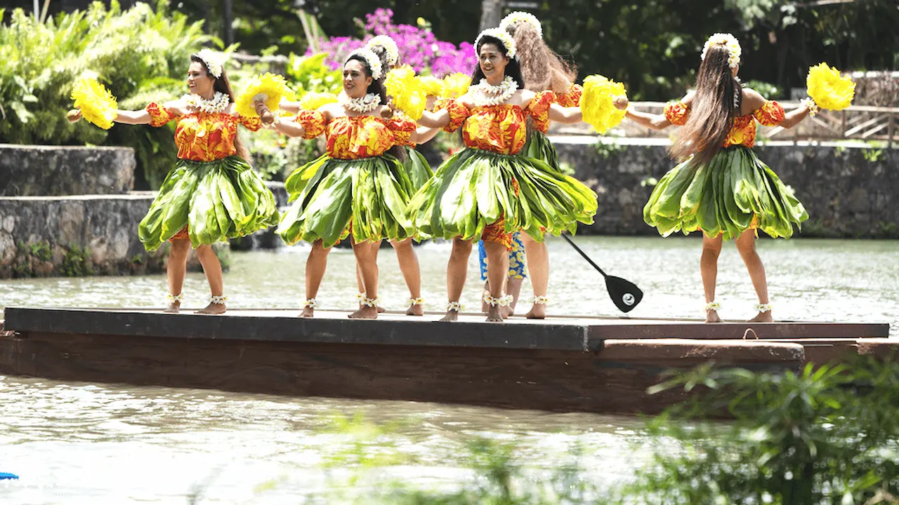 Women performing tī leaf skirts and red and yellow blouses.