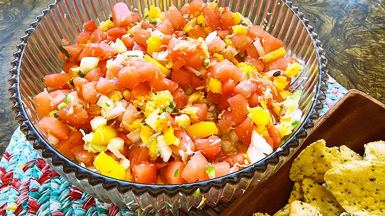 Watermelon, pineapple, mango, shredded coconut, lime juice, cucumber, onion, spicy pepper chopped and added to a glass bowl with tortilla chips.