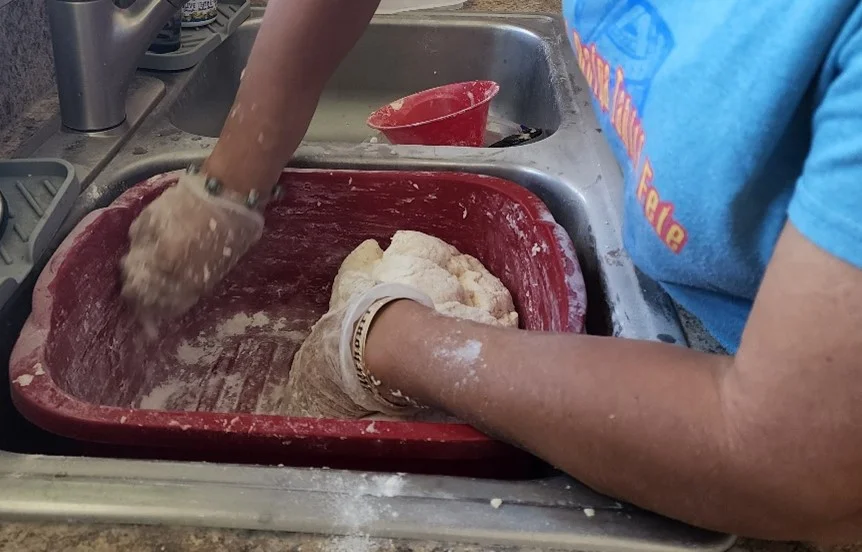 The dough, now combined. The sides of the bin are scraped with hands.