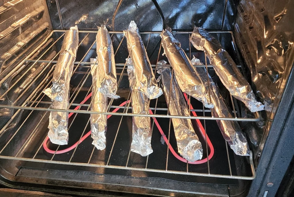 The dough is divided into 10 pieces of equal size, rolled into a log shape and wrapped with aluminum foil. Tahitian coconut bread in the oven, ready to bake.