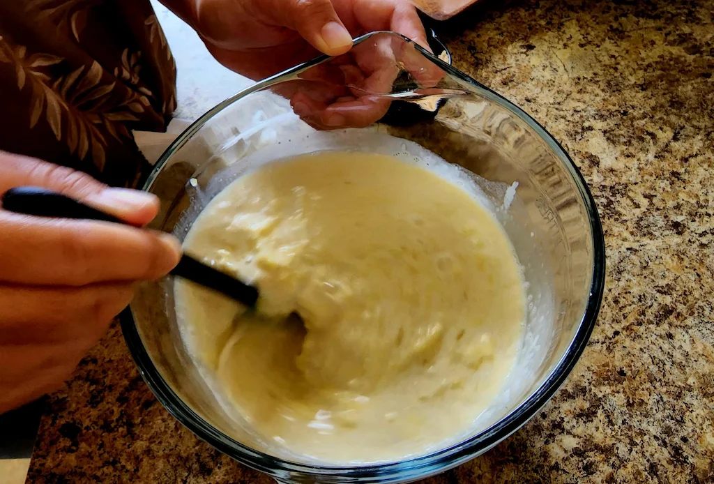 Stirring the vaifala with a whisk in a measuring cup after adding sugar.