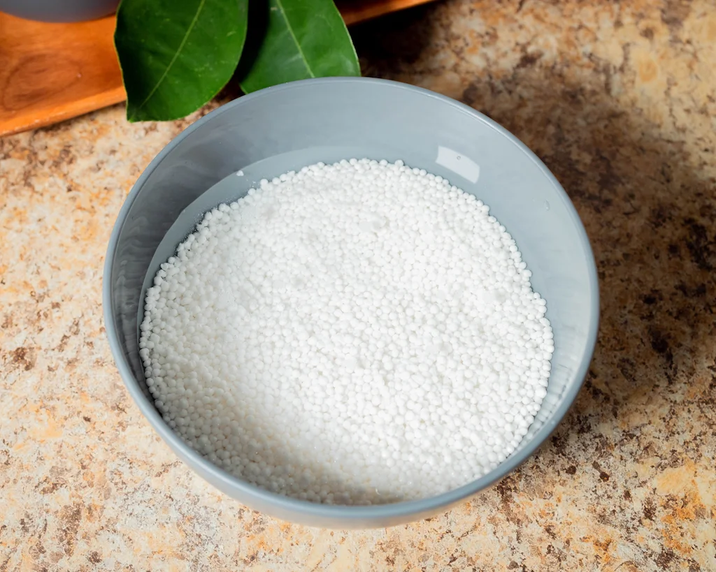 Small, white tapioca pearls placed in a bowl and soaking in water.